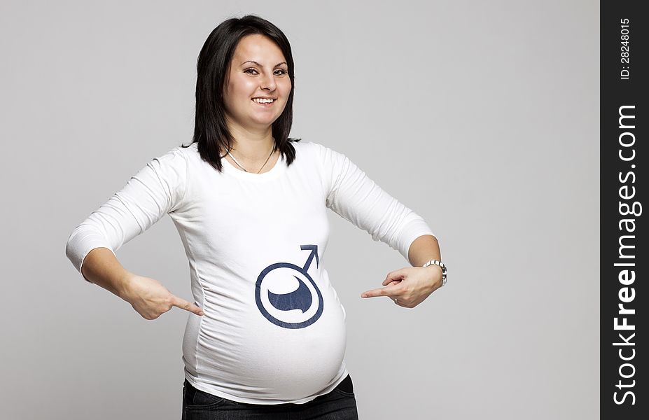 Pregnant woman pointing to boy sign on her shirt. Pregnant woman pointing to boy sign on her shirt