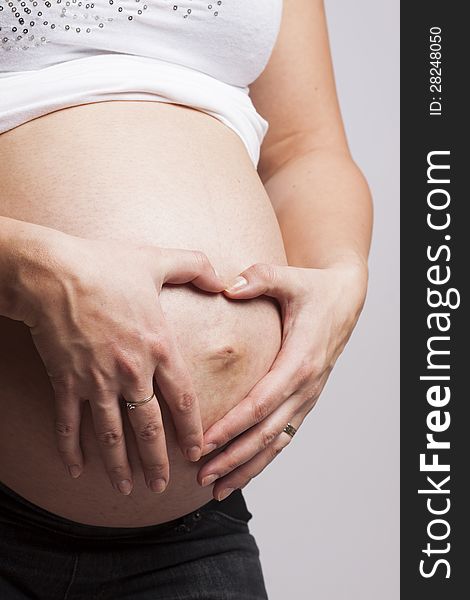 Hands of a pregnant woman making a heart with hands on her belly. Hands of a pregnant woman making a heart with hands on her belly