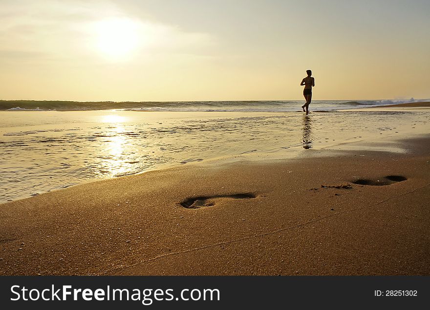 Woman jogging along the edge of the ocean.