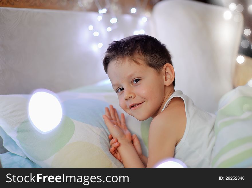 The little boy woke up in a children's cozy bed of lights. The little boy woke up in a children's cozy bed of lights