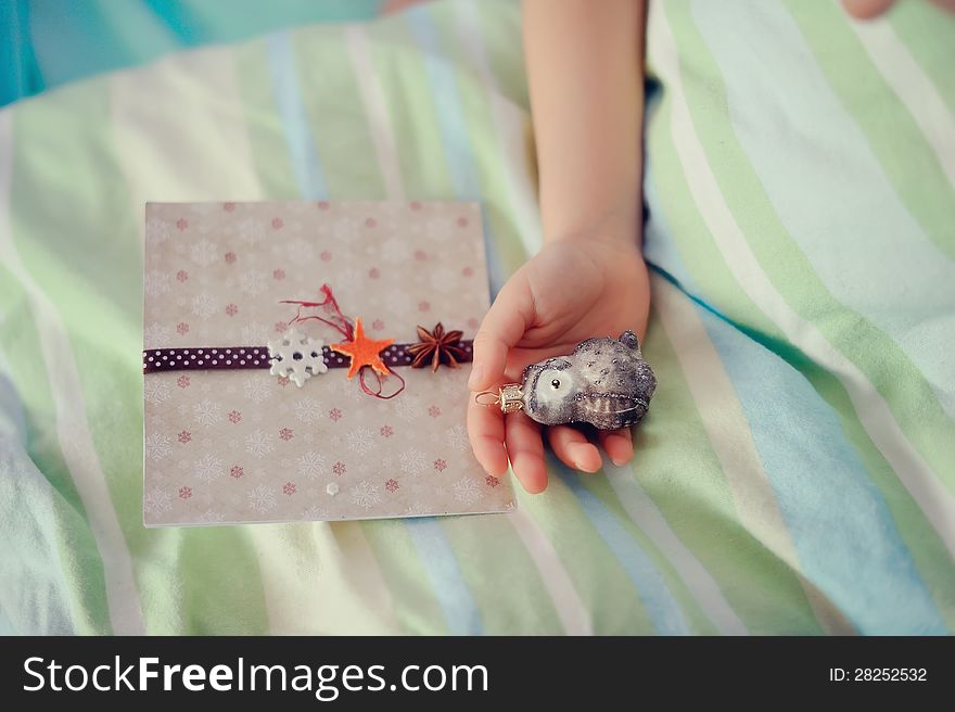 In the child's hand and toy lies next to a beautiful card. In the child's hand and toy lies next to a beautiful card