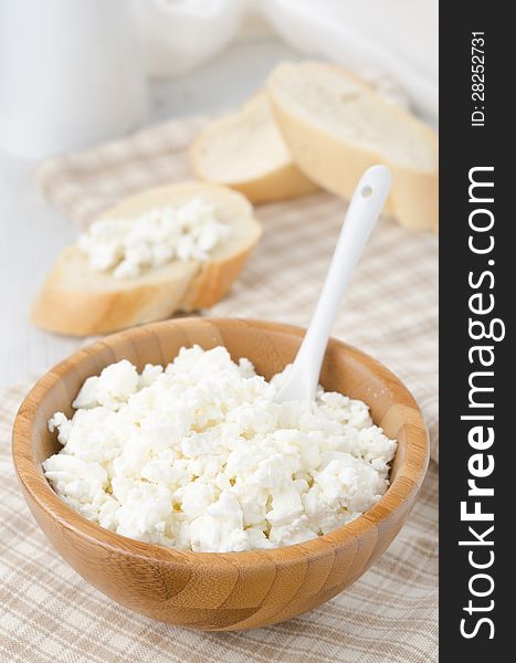 Bowl of cottage cheese and slices of baguette in the background