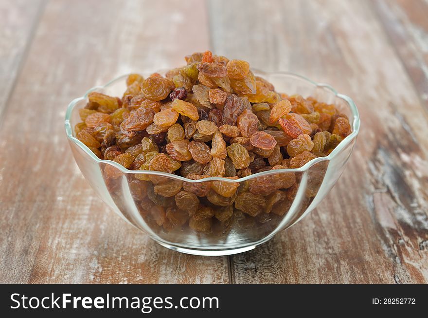 Glass bowl with sultana raisins closeup on wooden table