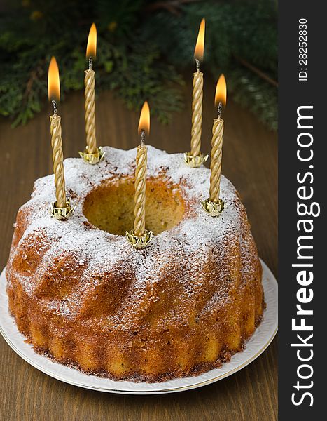 Orange and walnut cake with burning candles on a wooden table