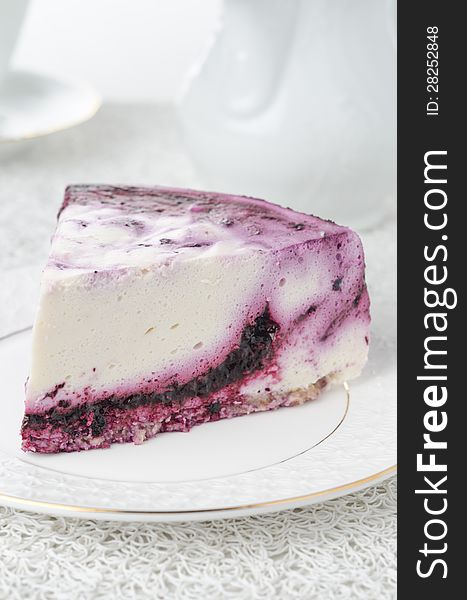 A piece of cheesecake with blueberries on a white plate on a white background. A piece of cheesecake with blueberries on a white plate on a white background