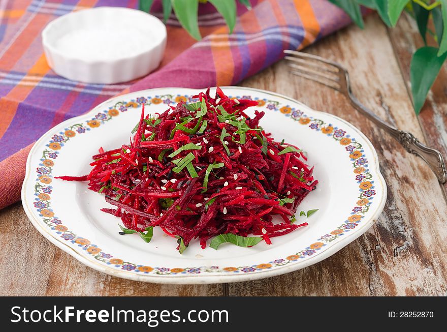 Salad of fresh beets and carrots with parsley sprinkled with sesame seeds on a plate