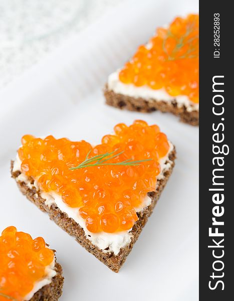 Sandwich With Red Caviar In The Form Of A Heart On White Plate,