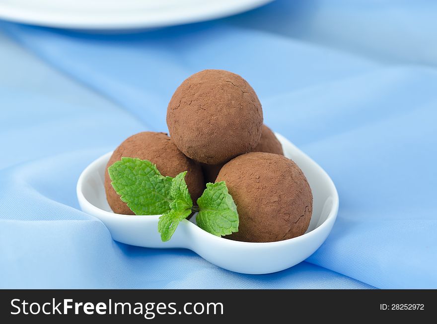 Chocolate truffle with fresh mint on a white plate