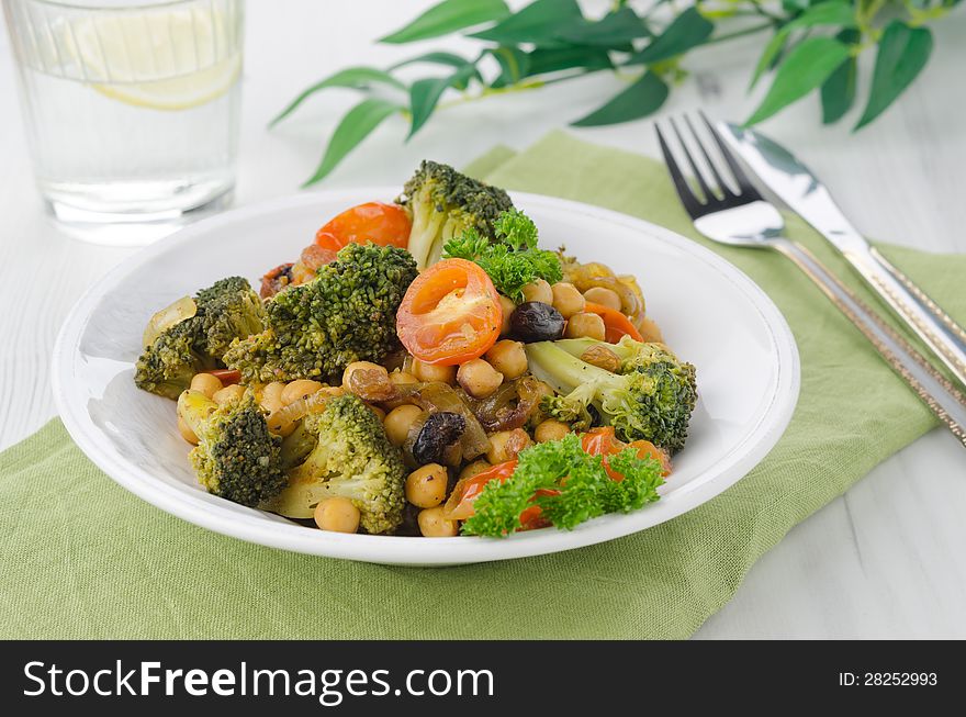 Warm salad with chickpeas, broccoli and raisins on the plate, horizontal