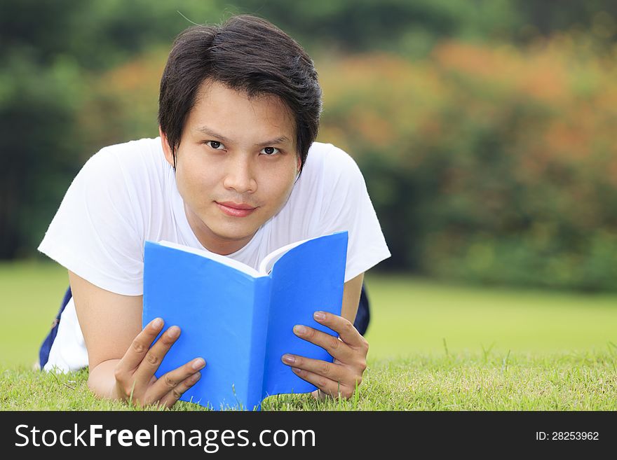 Young man open a book, look to the camera in outdoor