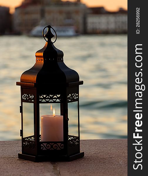 burning lantern. Sea and buildings on background