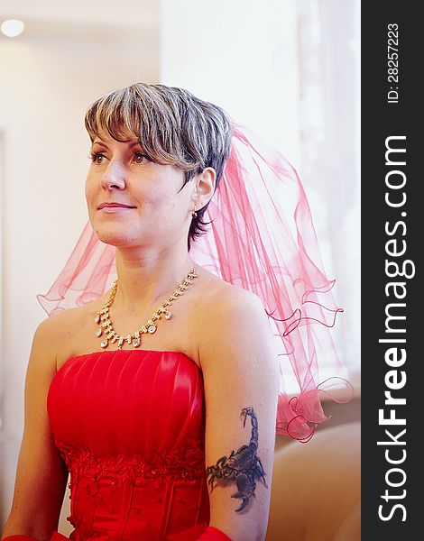 Portrait of the beautiful bride in a red dress on a light background