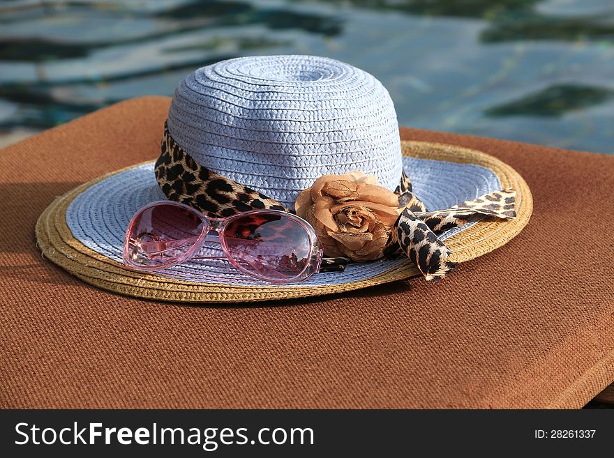 Sunglasses and sunhat closeup at swimming pool