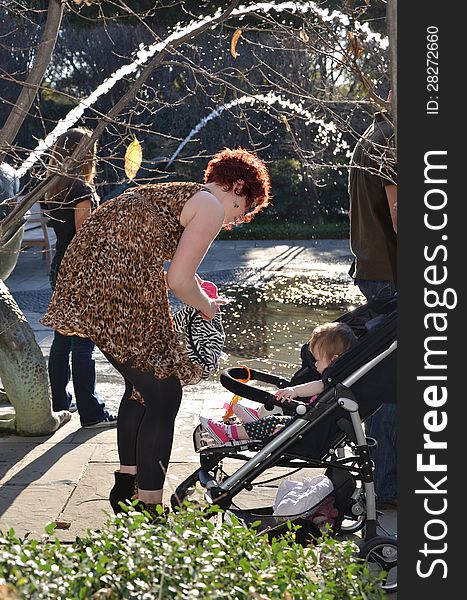 A mom with her one year old baby in a stroller in a park. Mom packing up baby stuff with stroller. A mom with her one year old baby in a stroller in a park. Mom packing up baby stuff with stroller.