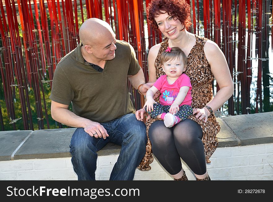 Diverse family portrait of an Asian men and white women with their baby girl. Beautiful multiracial family. Happy family at a park interacting.