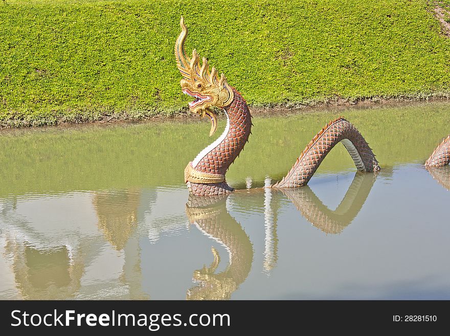 Naga statue. Swamp temple in green grass.