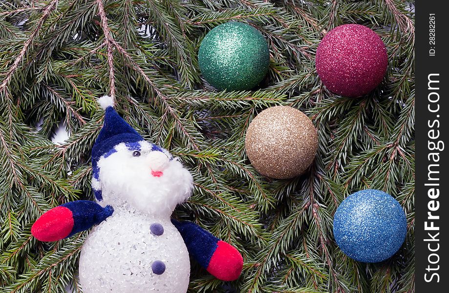 Colorful balls and snowman lying on spruce branches. background