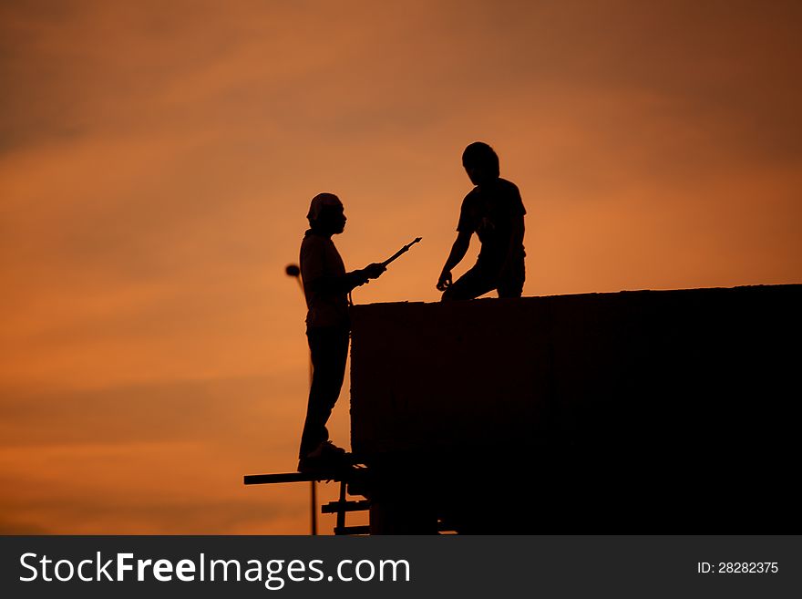 Silhouettes of worker welder at sunset