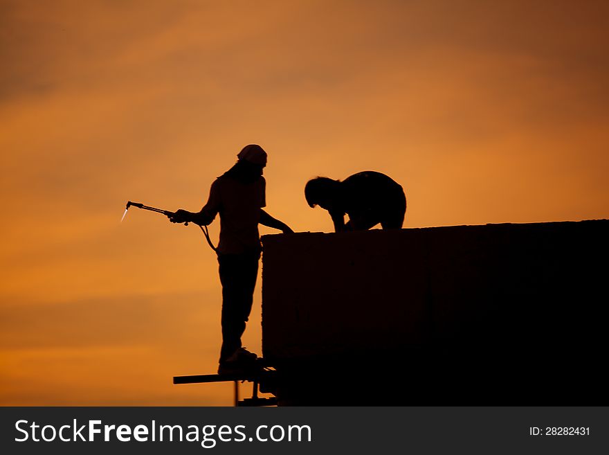 Silhouettes of worker welder at sunset