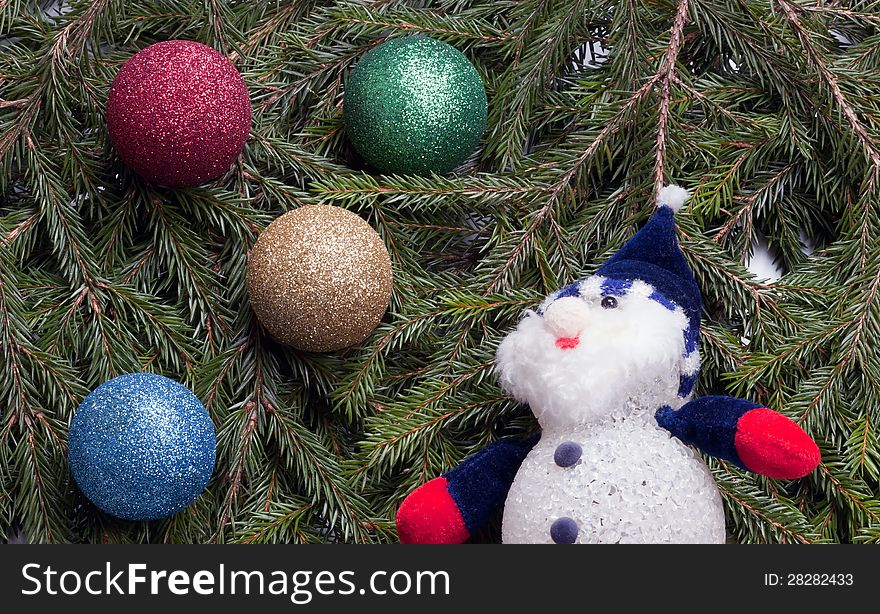 Colorful Balls And Snowman Lying On Spruce Branches.