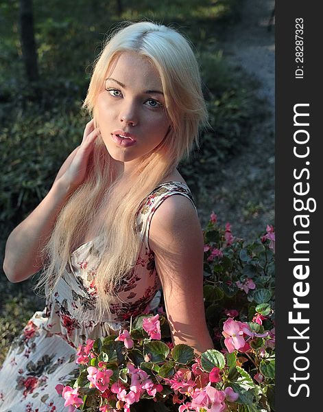 An image of a pretty woman sitting outside next to pink flowers. An image of a pretty woman sitting outside next to pink flowers