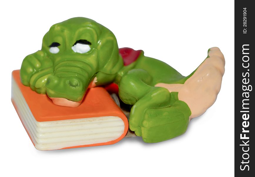 The photo shows a baby toy souvenir. The ceramic green crocodile, which lies on the book. The photo shows a baby toy souvenir. The ceramic green crocodile, which lies on the book.