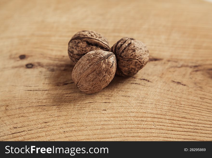 Three walnut on wooden background. Shallow depth of field.