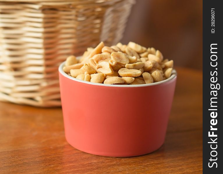 Close up of dried and salted nuts in red bowl.