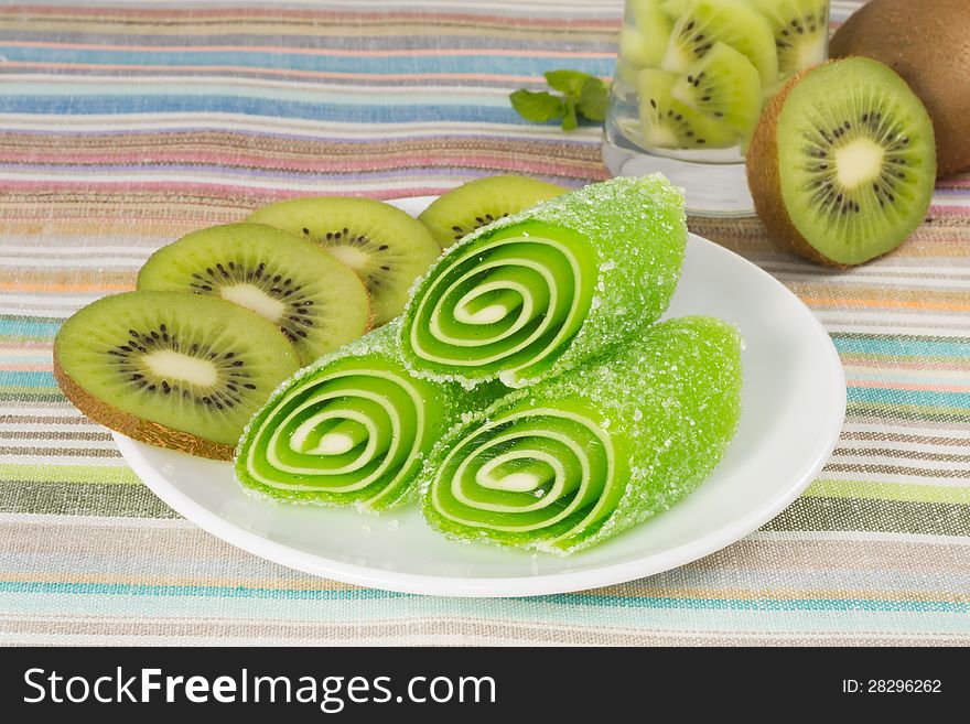 Green candy fruit on a plate with kiwi, closeup