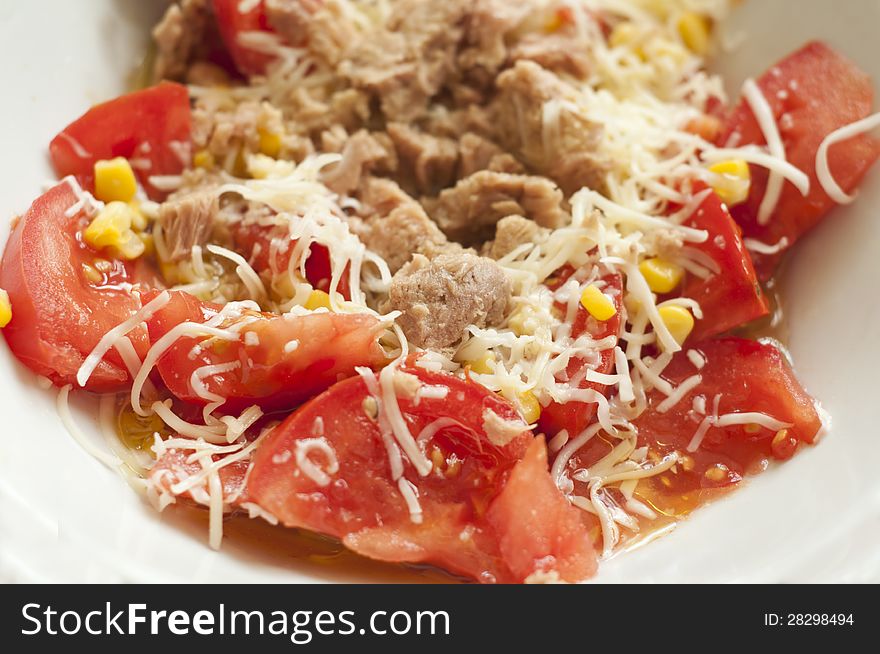 A plate of salad with tomatos and tuna