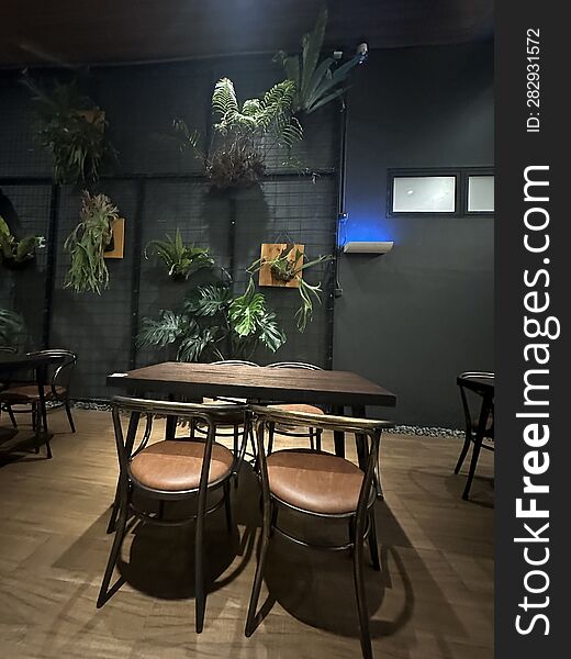 A corner of the restaurant that appears vacant with no customers. This is usually due to working hours or it being a weekday when fewer visitors come. Inside this room, there are several potted decorative plants hanging from a wire embedded in the wall, enhancing the natural beauty of the space.