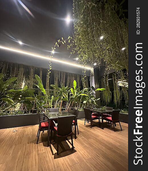 A minimalist room in a restaurant. It only contains a few chairs and tables, with decorative indoor plants placed nearby, serving as room adornments and adding to the natural ambiance. A minimalist room in a restaurant. It only contains a few chairs and tables, with decorative indoor plants placed nearby, serving as room adornments and adding to the natural ambiance.