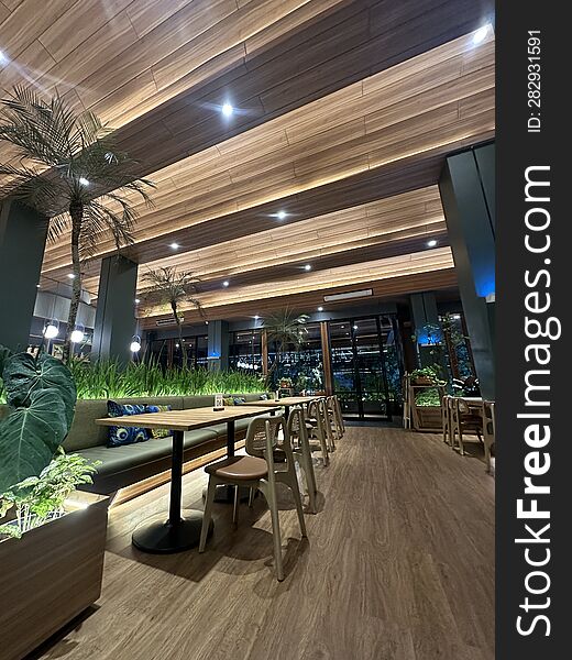 The interior design of the restaurant showcases a well-organized arrangement. Unique sofas and tables, paired with stylish chairs, are neatly arranged and adorned with strategically placed plants in various pots. The interior design of the restaurant showcases a well-organized arrangement. Unique sofas and tables, paired with stylish chairs, are neatly arranged and adorned with strategically placed plants in various pots.