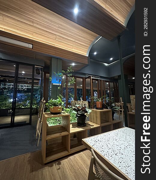 A neatly arranged wooden shelf in a restaurant. The shelf is placed in the middle of the restaurant to enhance the aesthetics. On top of it, plastic pots with beautiful minimalist plants are placed. A neatly arranged wooden shelf in a restaurant. The shelf is placed in the middle of the restaurant to enhance the aesthetics. On top of it, plastic pots with beautiful minimalist plants are placed.