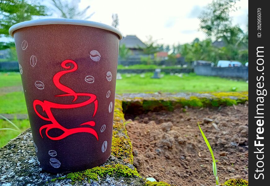 Close Up Photo Of A Paper Cup Filled With Coffee Against A City Park Background In The Morning