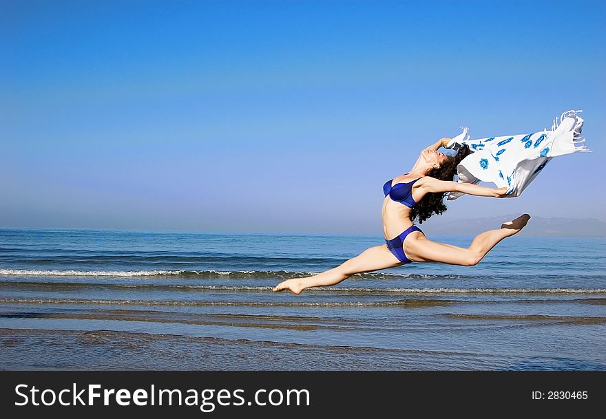 A jumping girl in bikini at the sea