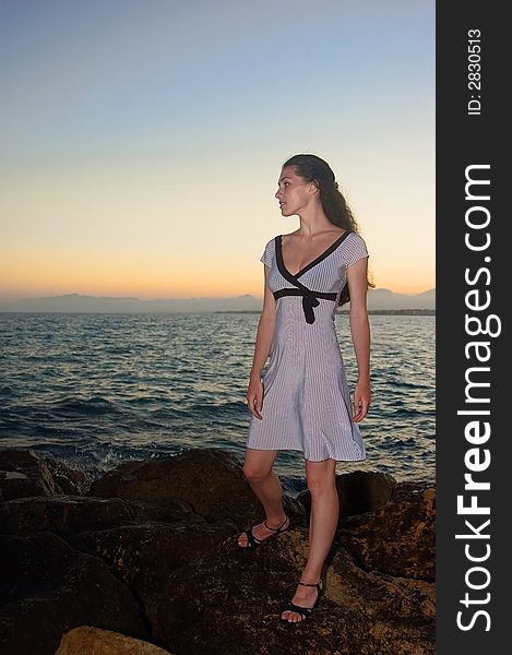 A girl standing on the seabank at the sunset