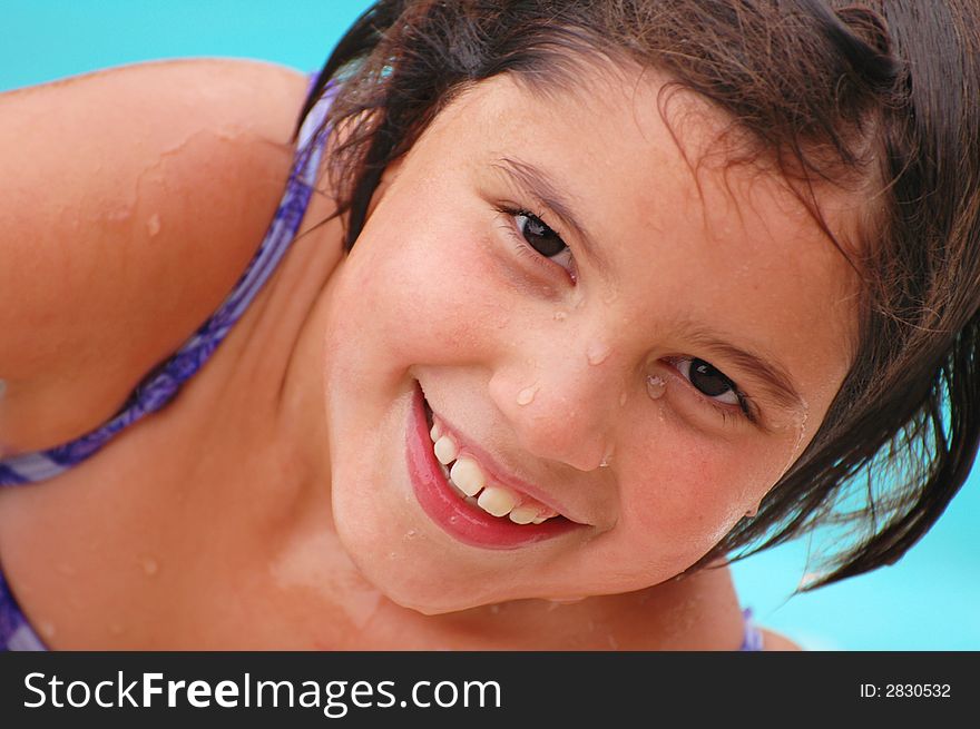 Close-up portrait of a happy elementary-aged swimmer, dripping wet from the pool.