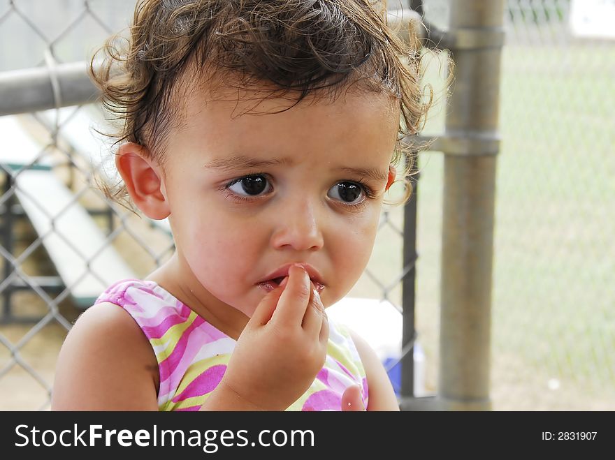 Cute Baby Girl Eating eating a snack at an outdoor event. Cute Baby Girl Eating eating a snack at an outdoor event