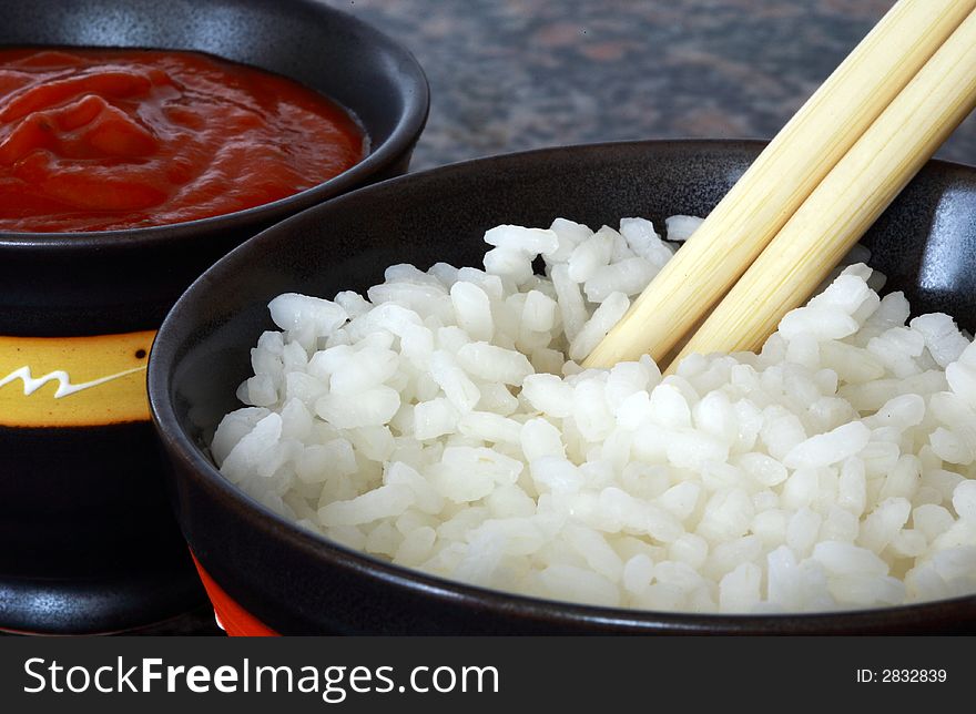 Chinesse rice and hot spice sauce bowl with two chopsticks. Chinesse rice and hot spice sauce bowl with two chopsticks