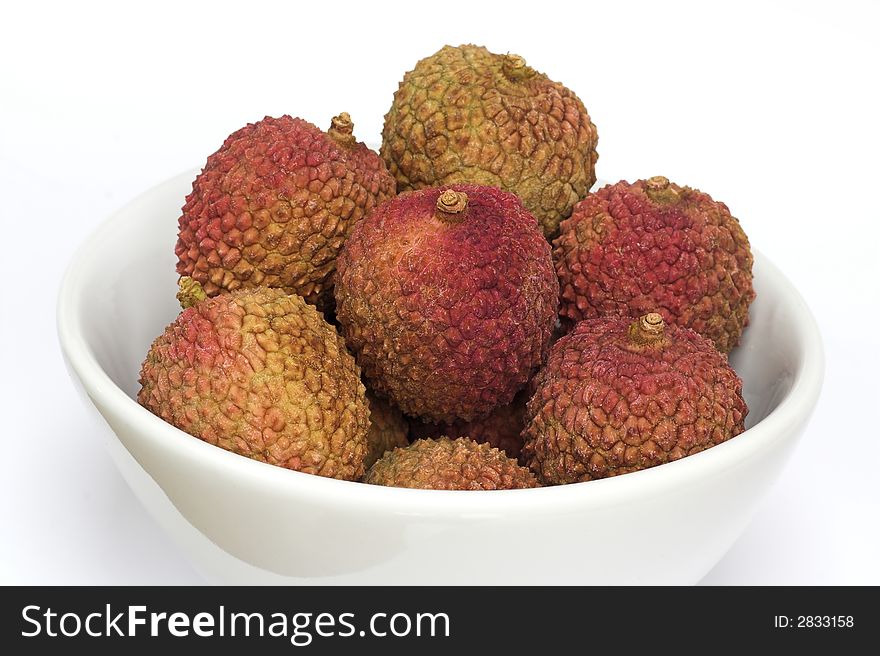 A white bowl filled with fresh litchis - on a white background.