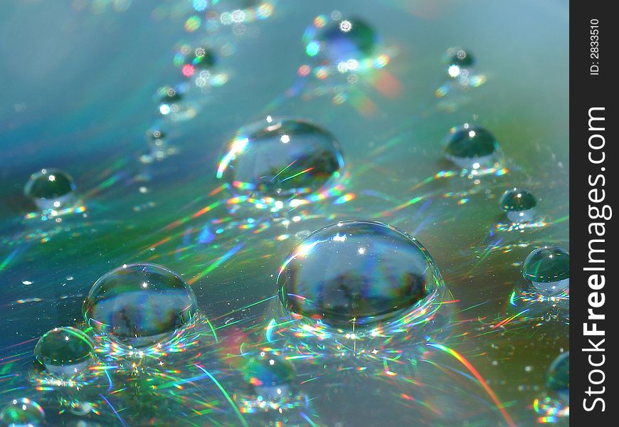 Water drops on a CD surface displaying all the colors of the rainbow. Water drops on a CD surface displaying all the colors of the rainbow