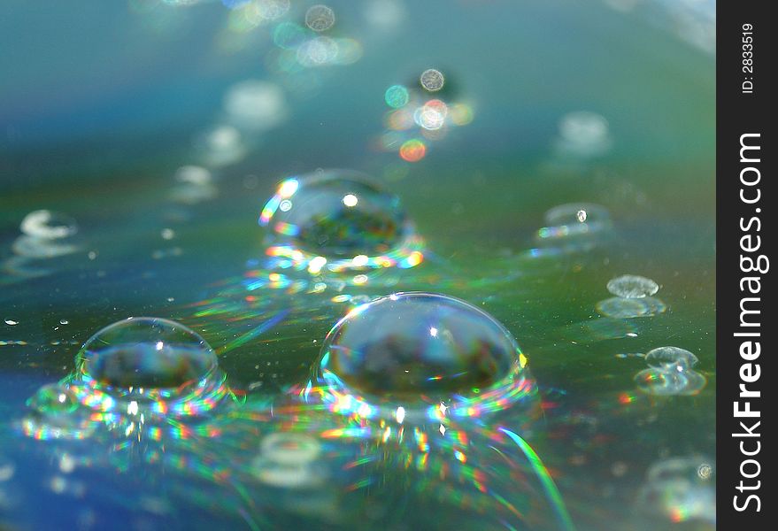 Water drops on a CD surface displaying all the colors of the rainbow. Water drops on a CD surface displaying all the colors of the rainbow