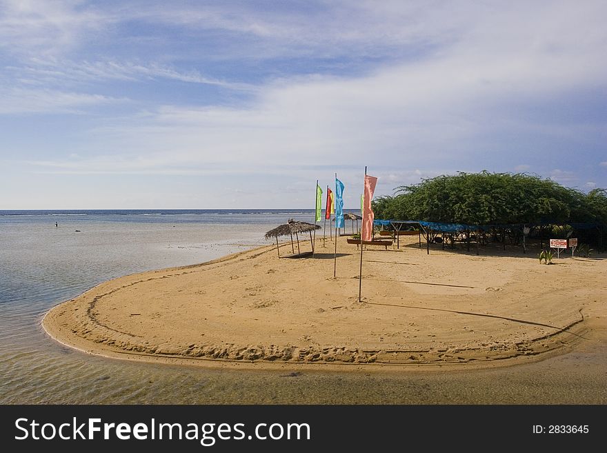 Flags lined up with a hut by the seashore. Flags lined up with a hut by the seashore