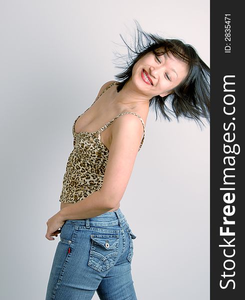 A young, sexy, and attractive Asian woman in jeans and bustier, with her hair blowing in the wind. A young, sexy, and attractive Asian woman in jeans and bustier, with her hair blowing in the wind.