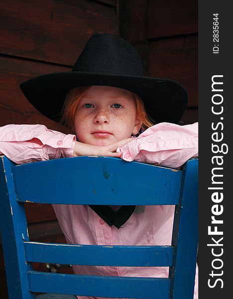 Little cowgirl sitting on a chair