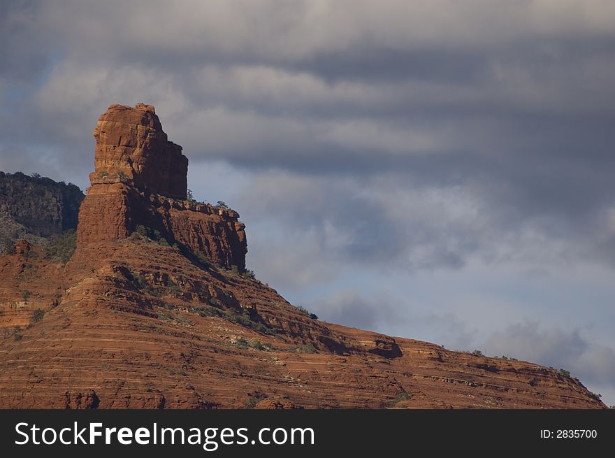 Red colored sandstone cliff near sedona, arizona with cloudy sky in background. Red colored sandstone cliff near sedona, arizona with cloudy sky in background