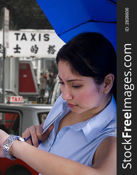 Young woman with an umbrella looking at her watch and taxis in the background. Young woman with an umbrella looking at her watch and taxis in the background.