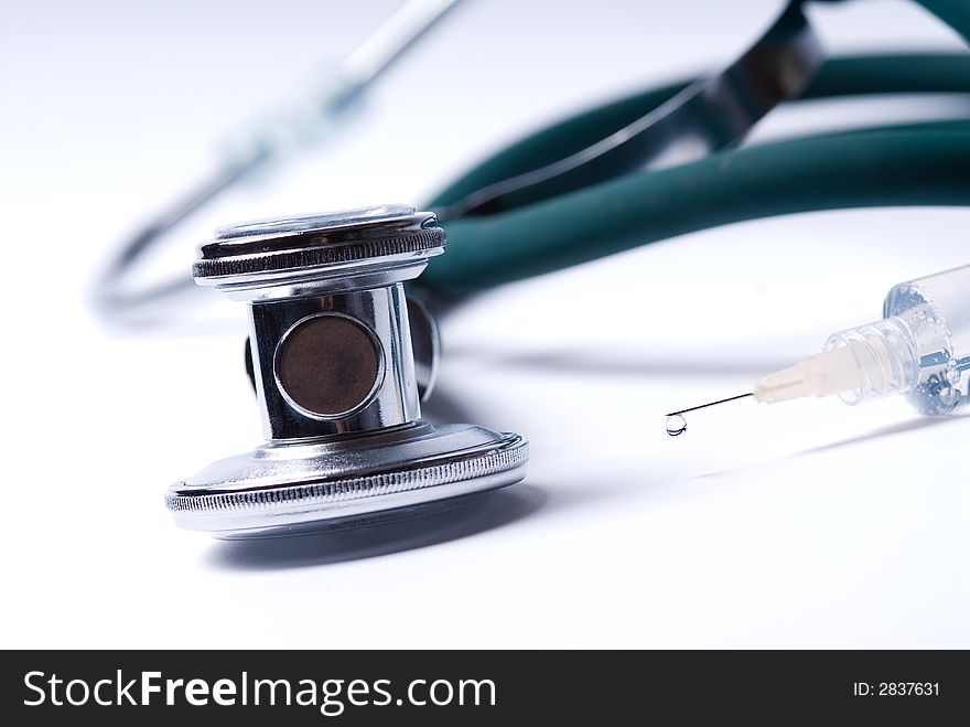 Stethoscope and a syringe in green on an isolated white background