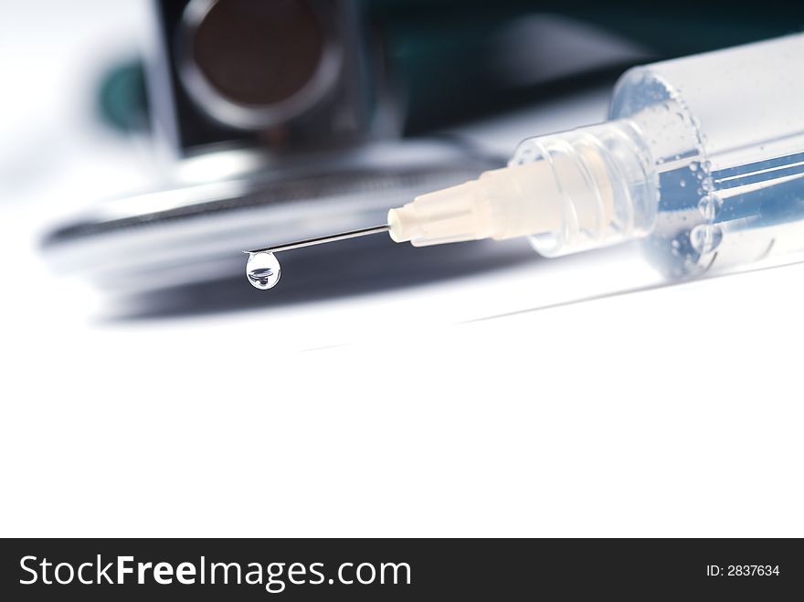 Stethoscope and a syringe in green on an isolated white background